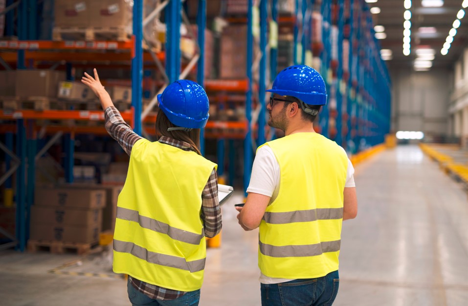 Two warehouse team members reviewing inventory on the floor